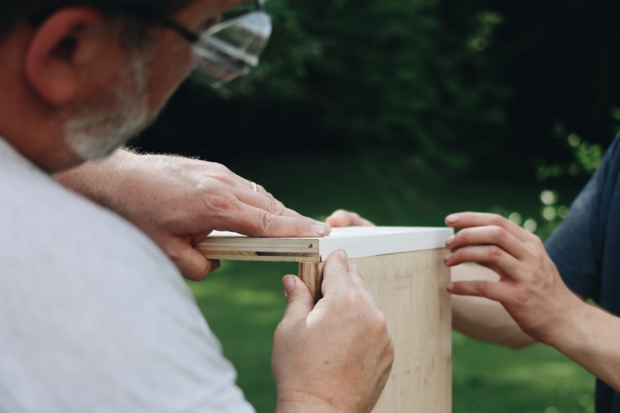 Two people fitting a white-topped shelf board onto the plywood cabinet they are building