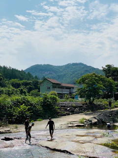 A group of adventurers crossing a crystal-clear stream near Laguna de San Diego surrounded by lush greenery.