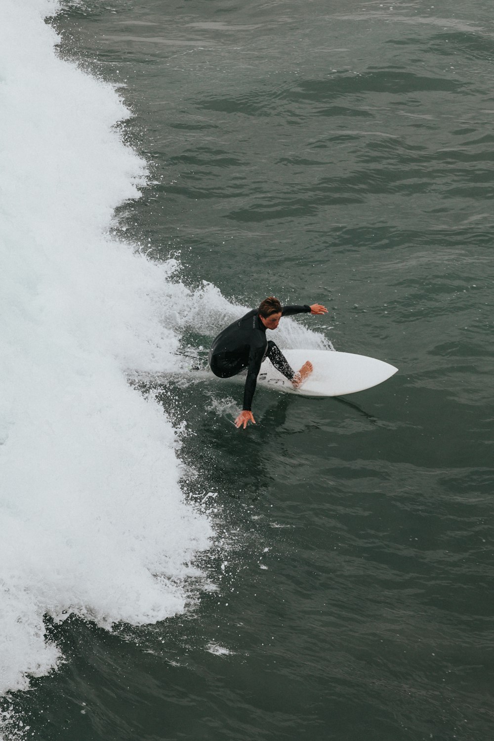 hombre en traje de neopreno negro surfeando en las olas del mar durante el día