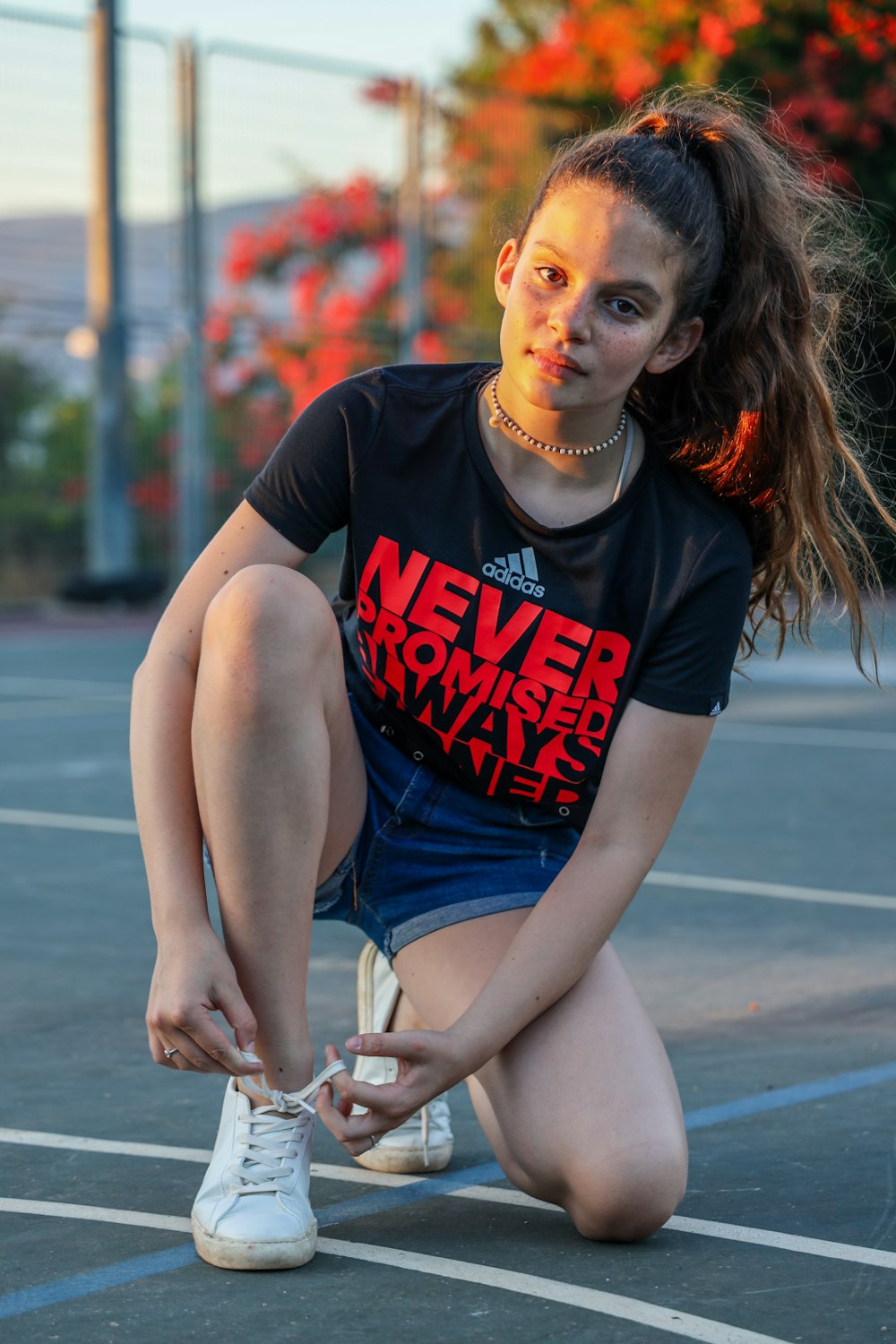 woman in black and red crew neck t-shirt and blue denim shorts sitting on gray