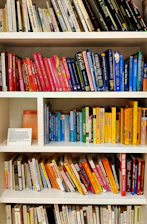 yellow blue red and green books on white wooden shelf
