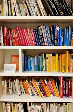 yellow blue red and green books on white wooden shelf