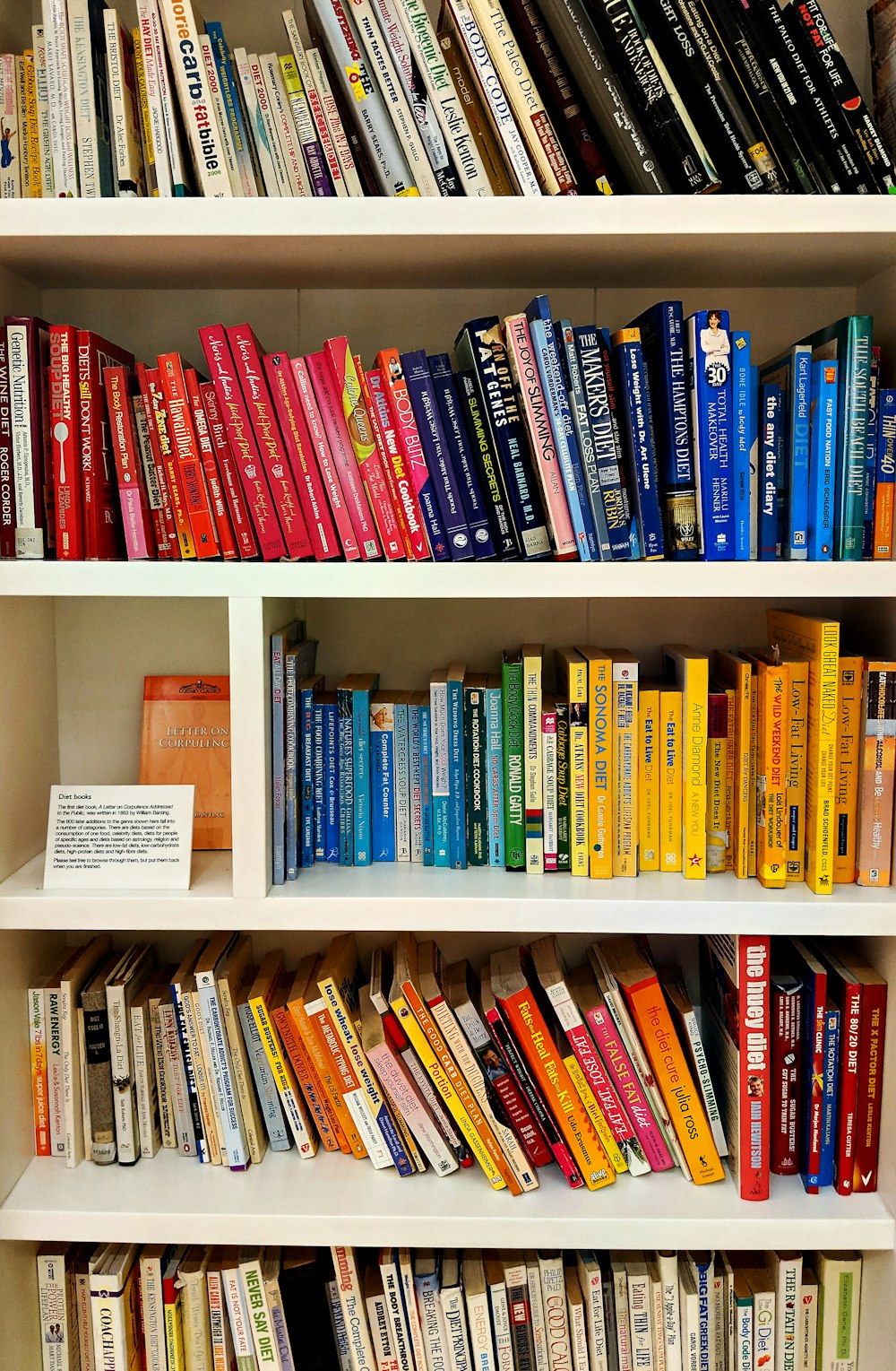 yellow blue red and green books on white wooden shelf