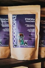 A package of coffee labeled 'GOOD PEOPLE' with details about Ethiopian Yirgacheffe coffee featuring blueberry, strawberry, honey, and chocolate notes. The packaging includes artistic illustrations and handwritten notes regarding the roast date and roaster’s name.