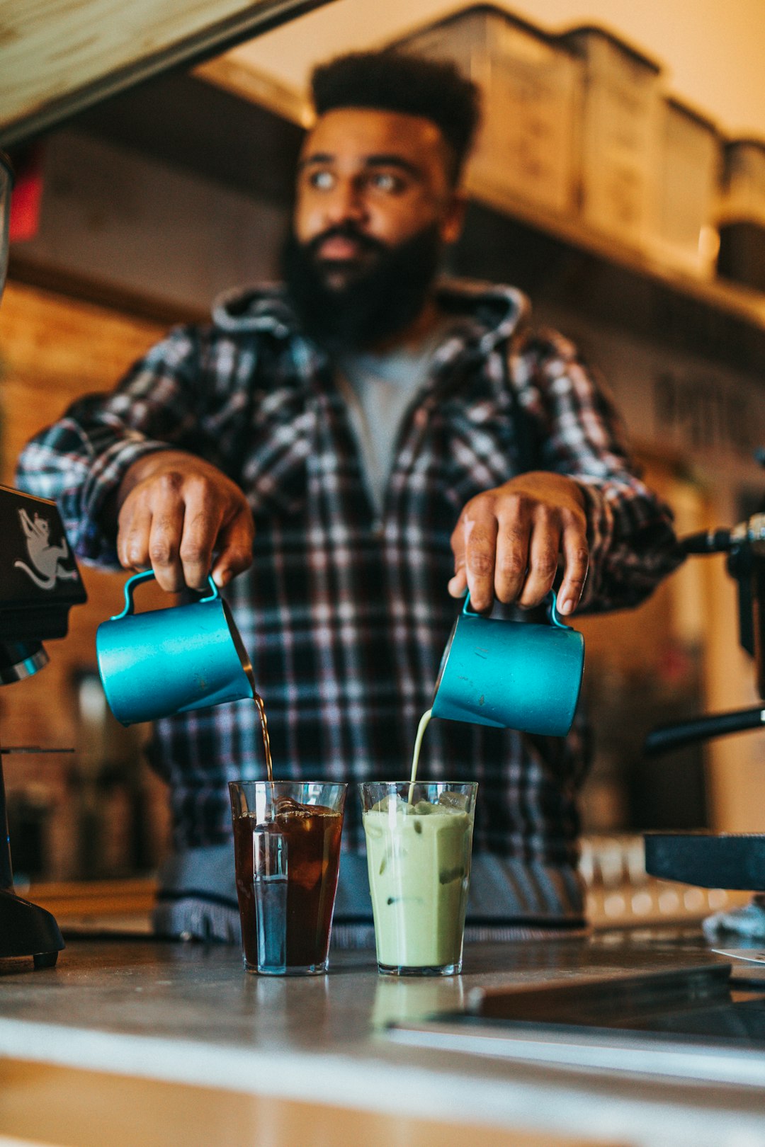 man pouring blue liquid on clear drinking glass