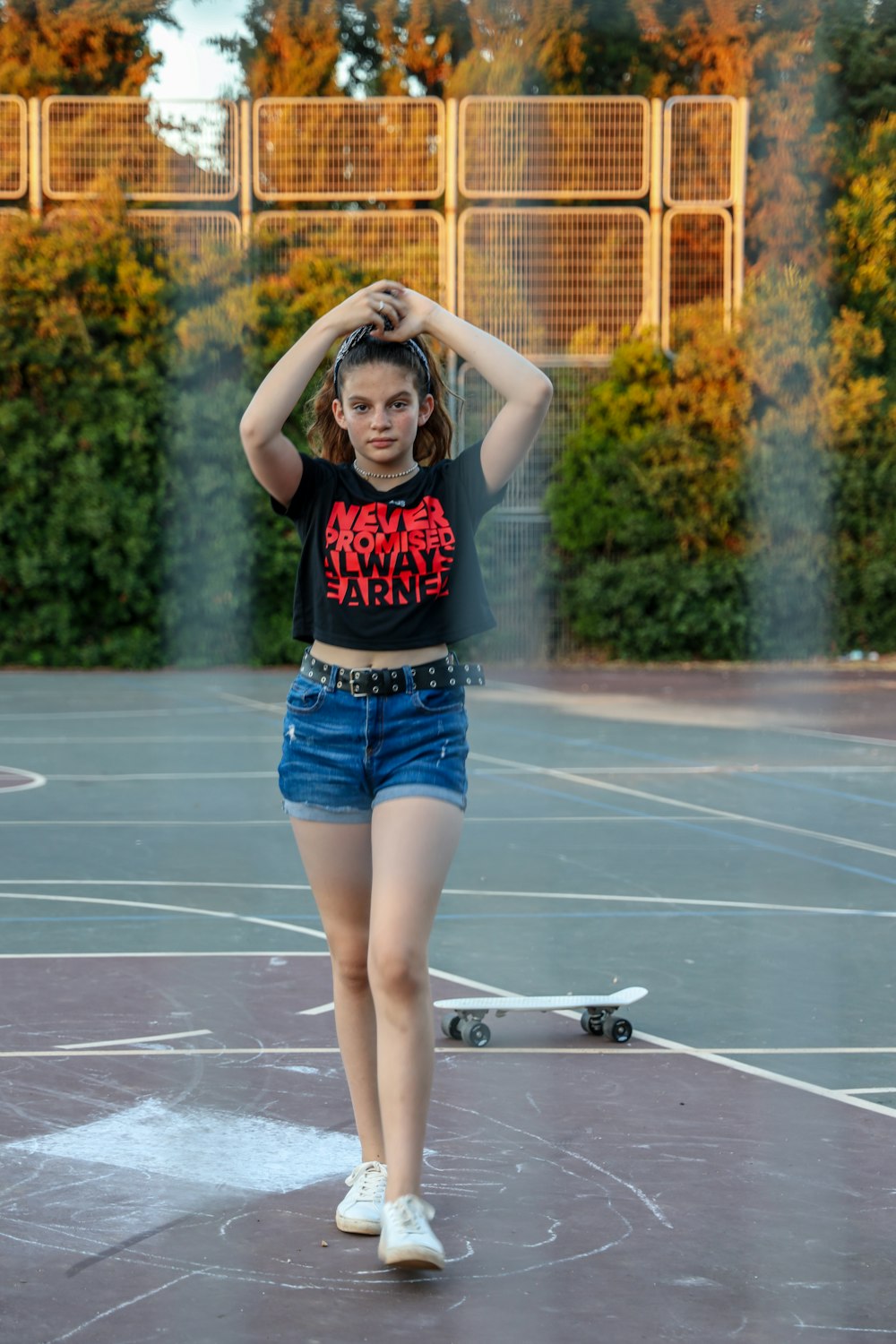 Mujer con camiseta sin mangas roja y pantalones cortos de mezclilla azules de pie en la cancha de baloncesto