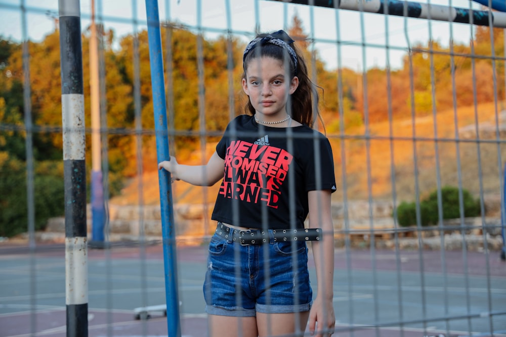 girl in black and red crew neck t-shirt and blue denim shorts standing on blue