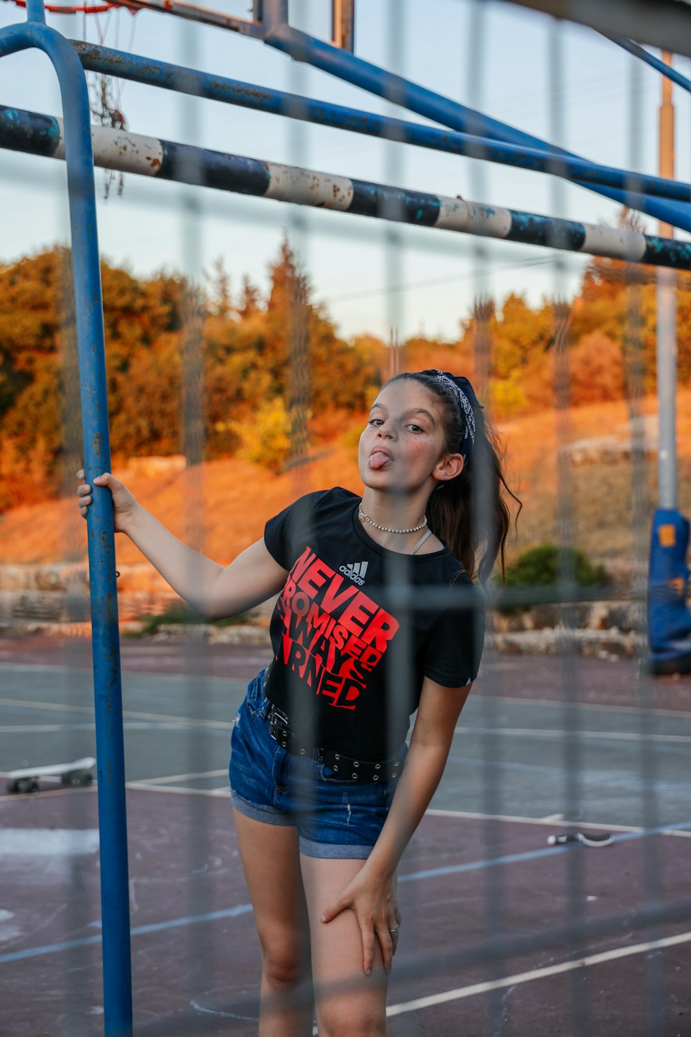 Donna in t-shirt girocollo nera e rossa e pantaloncini di jeans blu in piedi sul ponte