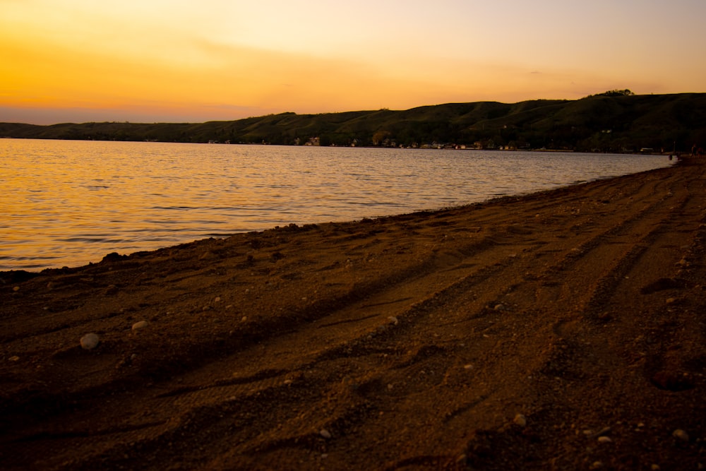 body of water near mountain during sunset