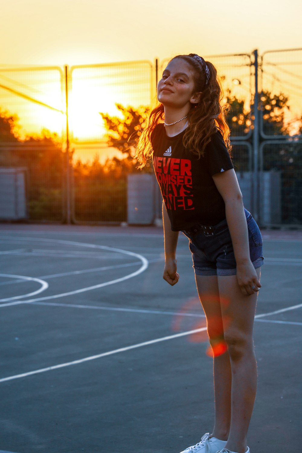 mulher na camiseta preta e branca do pescoço da tripulação e shorts jeans azuis em pé no basquete