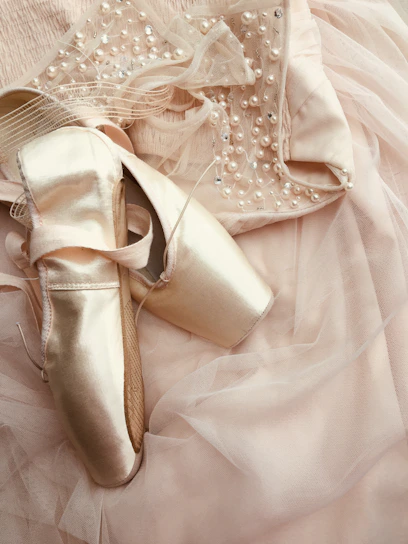 A pair of elegant pointe shoes tied with satin ribbons against a soft pastel background.