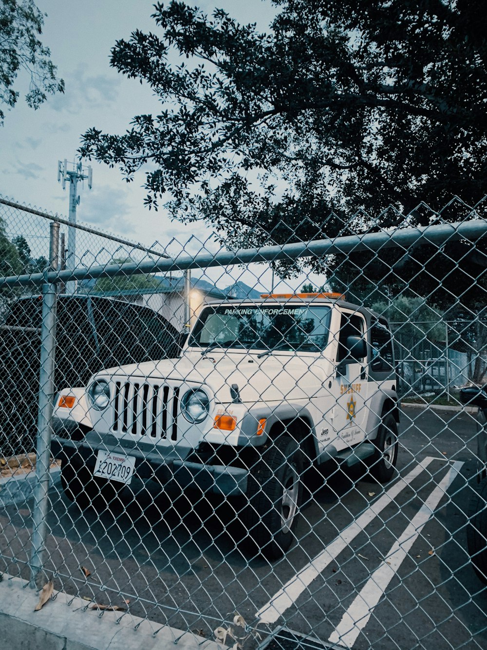 Jeep Wrangler blanc et noir garé à côté d’une clôture en métal gris