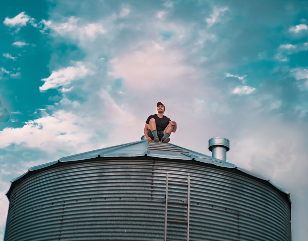 woman in white long sleeve shirt sitting on gray round roof under blue and white sunny