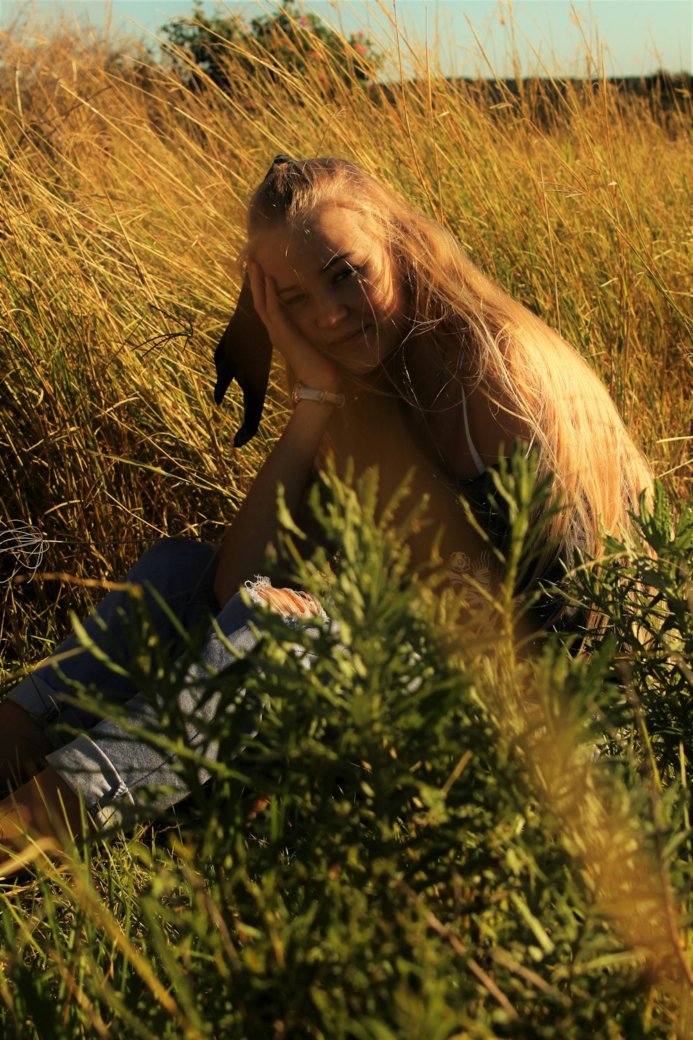 woman in black tube dress lying on green grass field during daytime