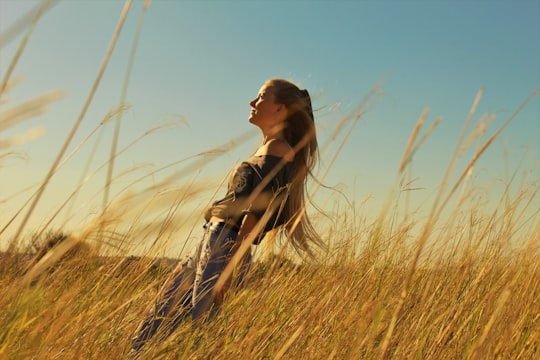 woman in brown and black floral shirt standing on brown grass field during daytime in Port Alfred South Africa