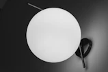 Minimalist lamp with a white spherical shade resembling a full moon on a sleek stand.