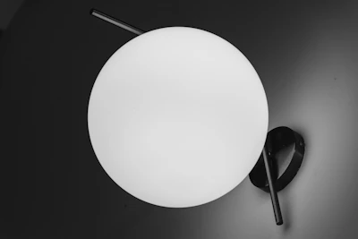 Minimalist lamp with a white spherical shade resembling a full moon on a sleek stand.