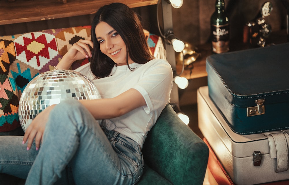 woman in white shirt and blue denim jeans sitting on green sofa