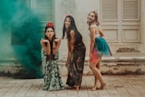3 women in black and green dress standing on gray concrete floor