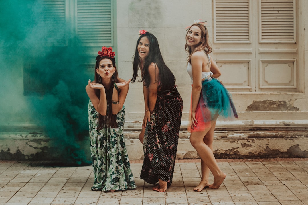 3 women in black and green dress standing on gray concrete floor