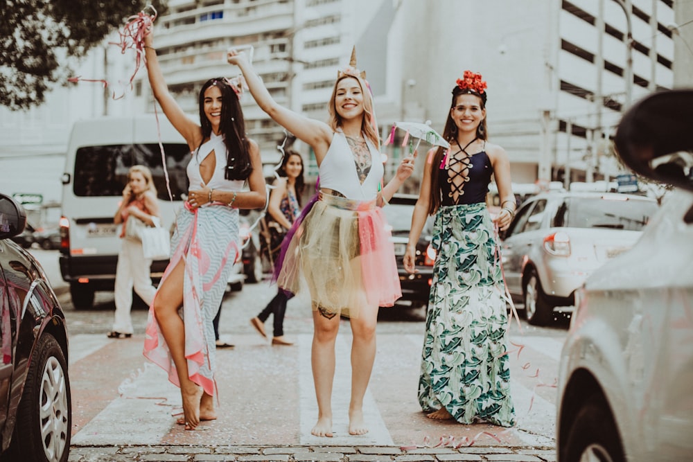 3 women in white and black floral dresses dancing on the street during daytime