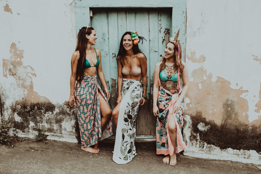 2 women in floral dress standing beside white wall during daytime