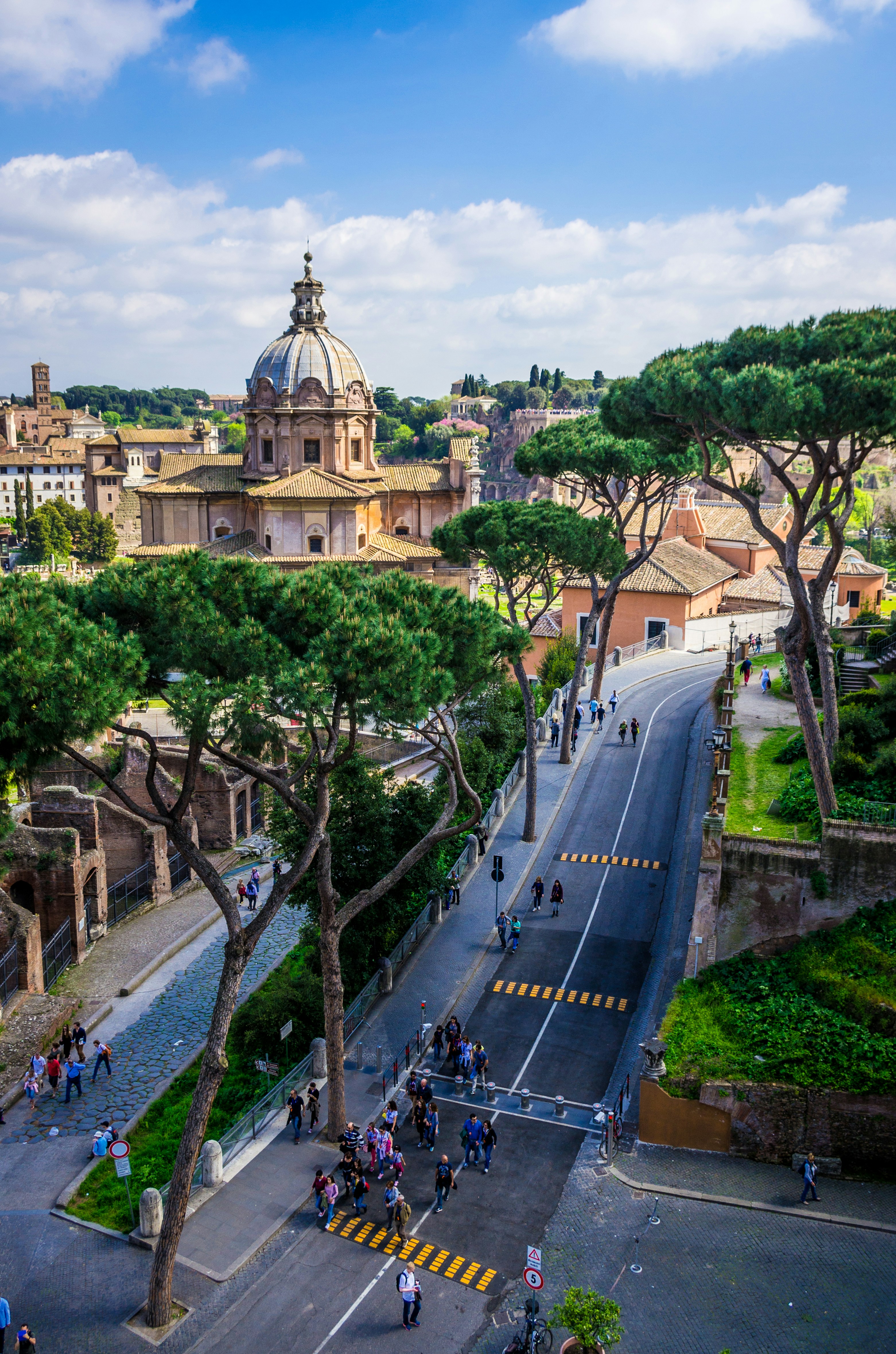 people walking on road near trees and building during daytime