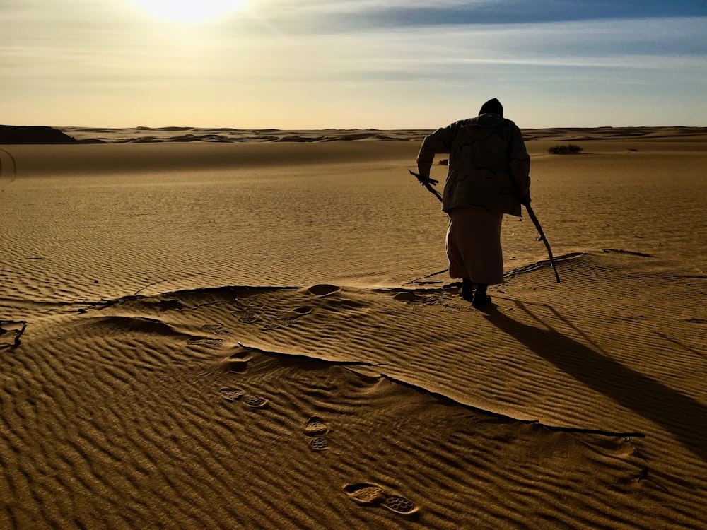 man in black shirt and black pants standing on brown sand during daytime