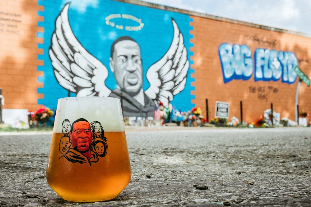 a glass of beer sitting on the ground in front of a building