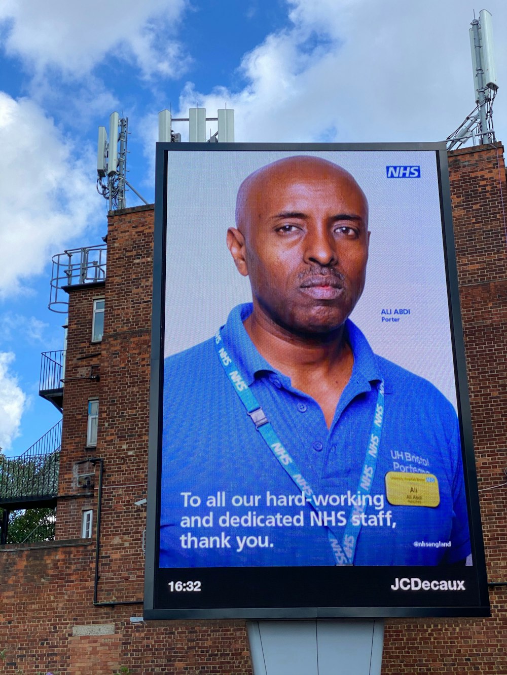 man in blue polo shirt standing near brown brick building during daytime