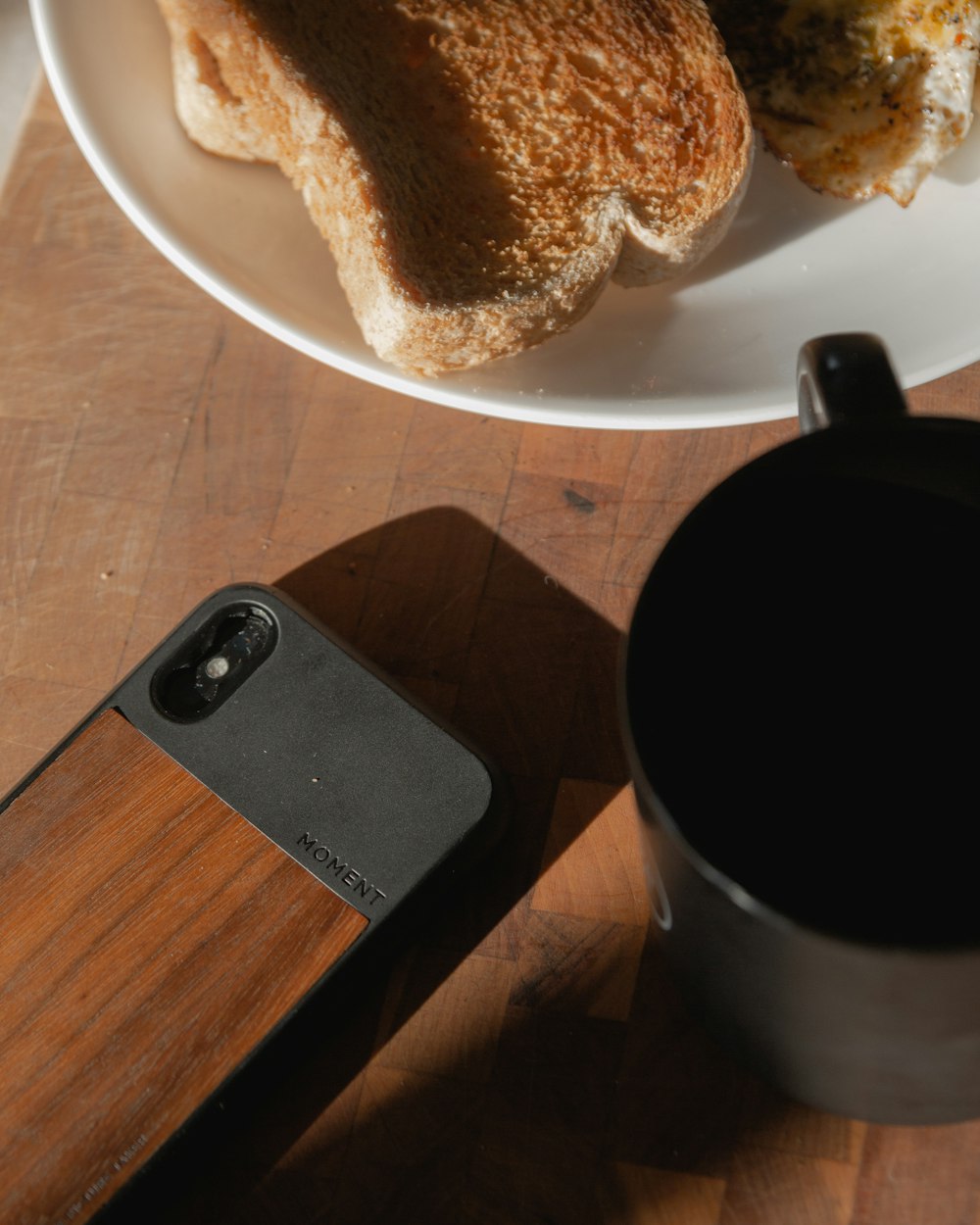 茶色の木製テーブルに黒いセラミックのマグカップ