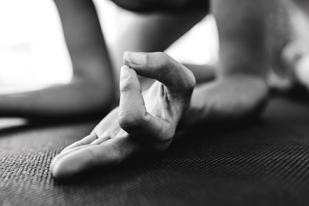 A close-up of hands in a meditative pose surrounded by nature.