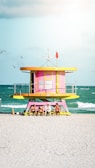 pink and yellow wooden lifeguard house on beach during daytime