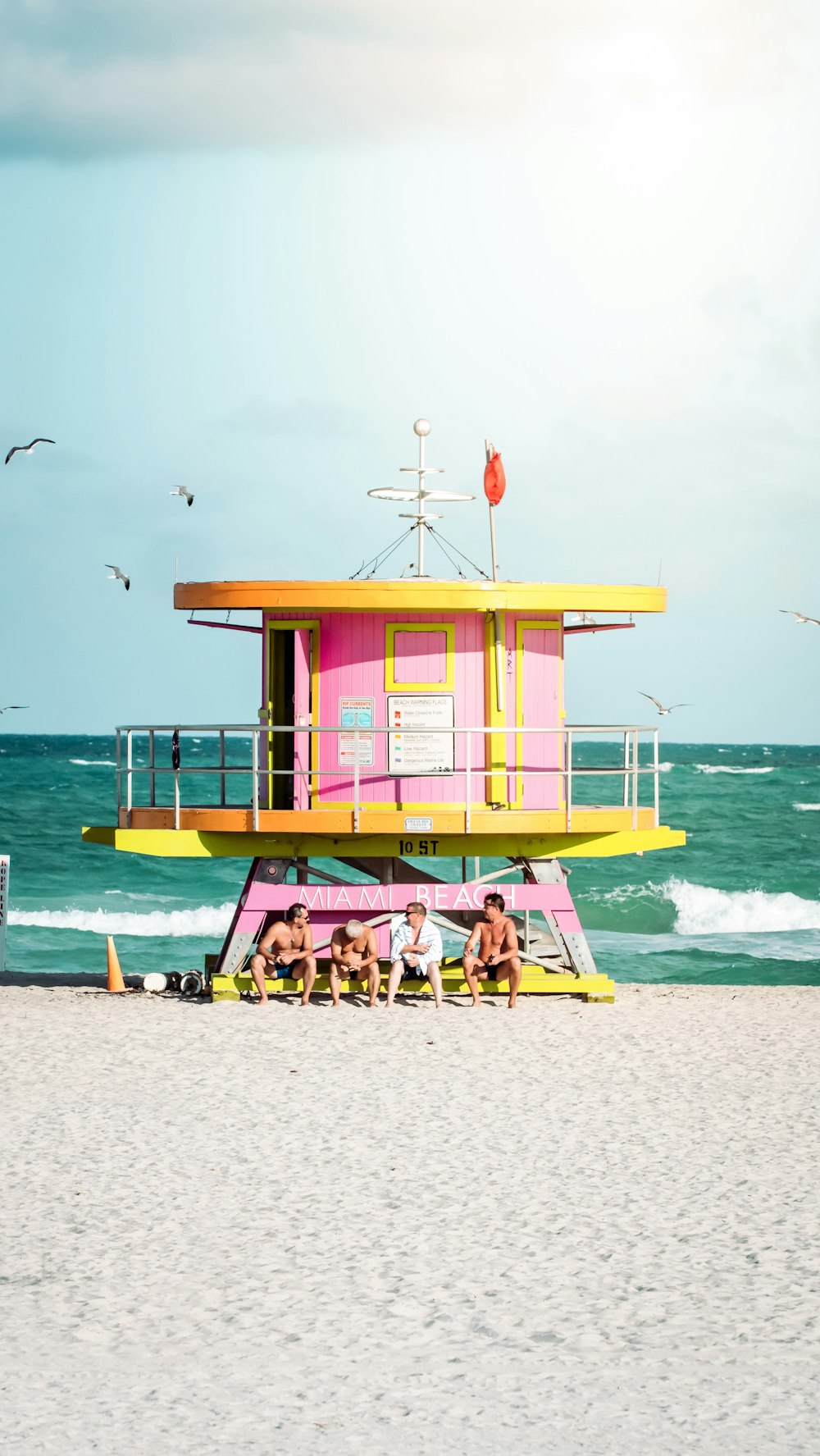maison de sauveteur en bois rose et jaune sur la plage pendant la journée