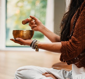 woman in brown knit sweater holding brown ceramic cup