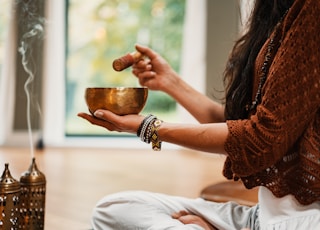 woman in brown knit sweater holding brown ceramic cup