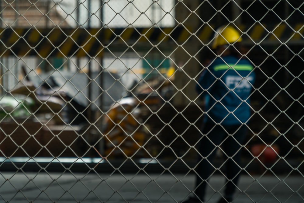 man in blue jacket standing beside gray metal fence