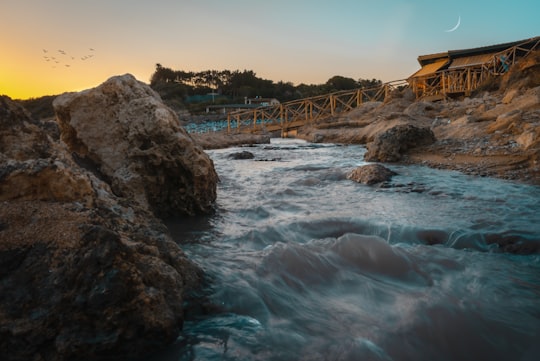 brown wooden bridge over water in Le Castella Italy