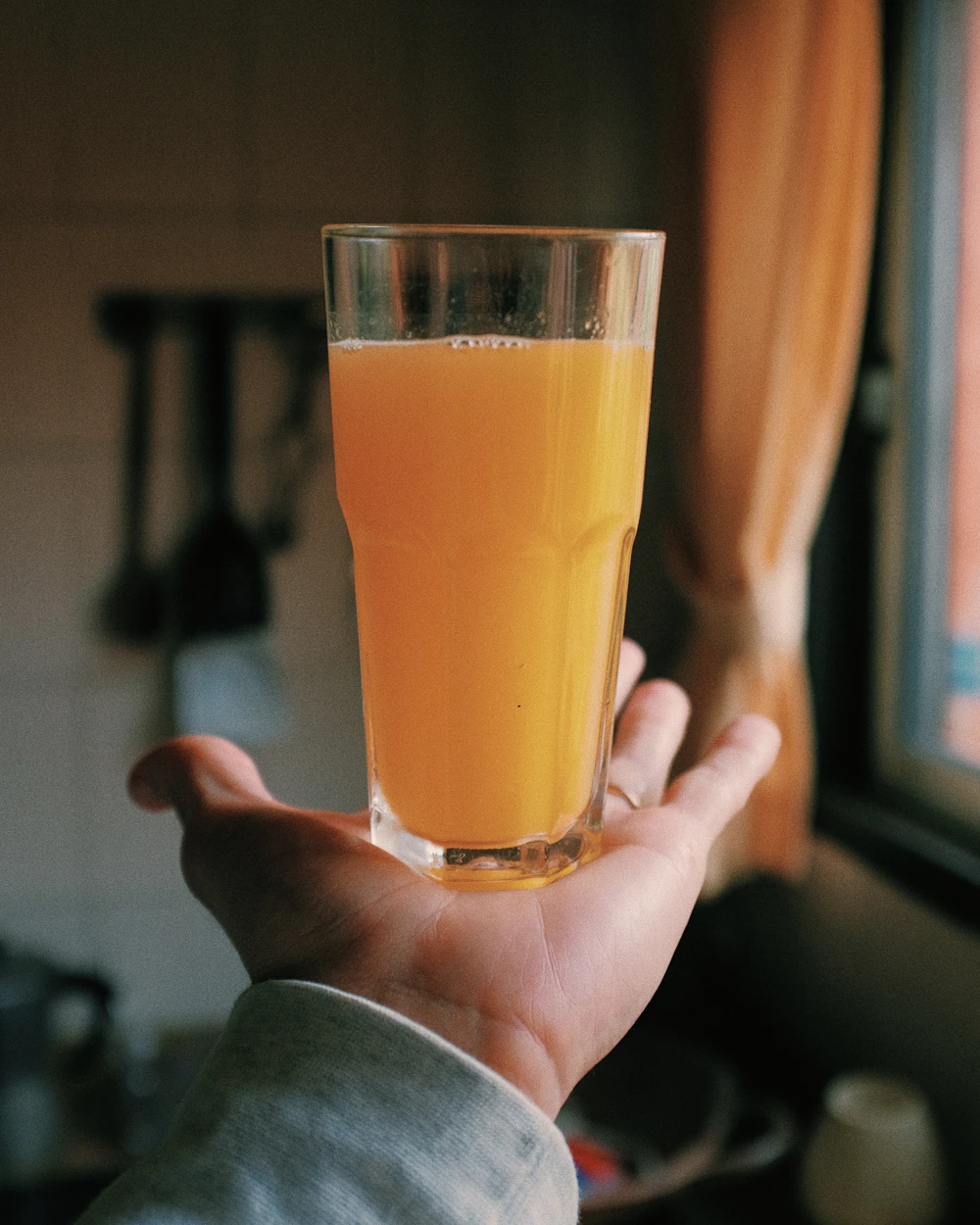 Pessoa segurando um copo de suco de laranja