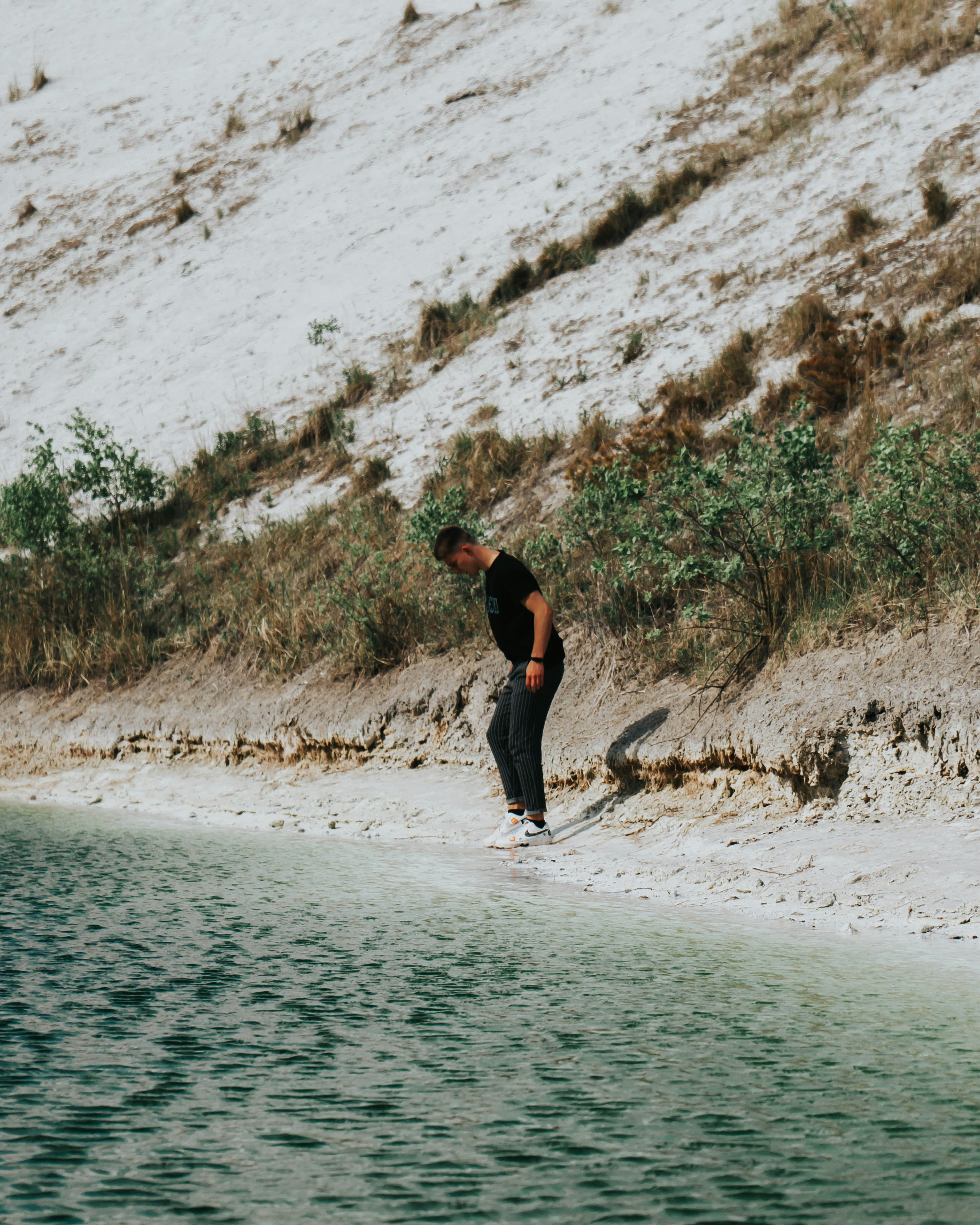man in black jacket and black pants standing on seashore during daytime