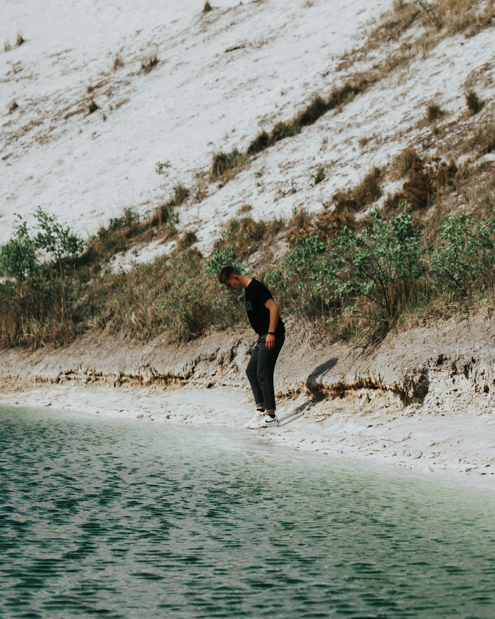 man in black jacket and black pants standing on seashore during daytime