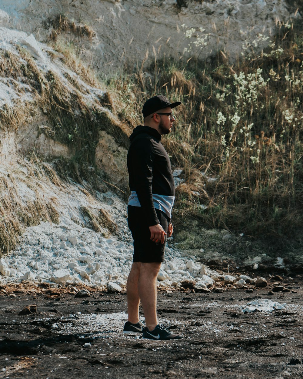 woman in black jacket and black shorts standing on rocky road during daytime