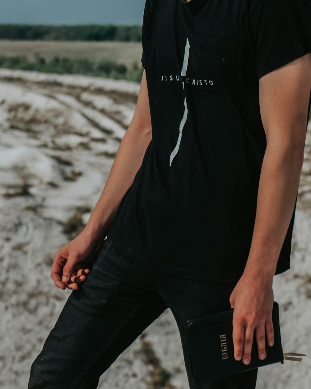 man in black pants standing on gray sand during daytime