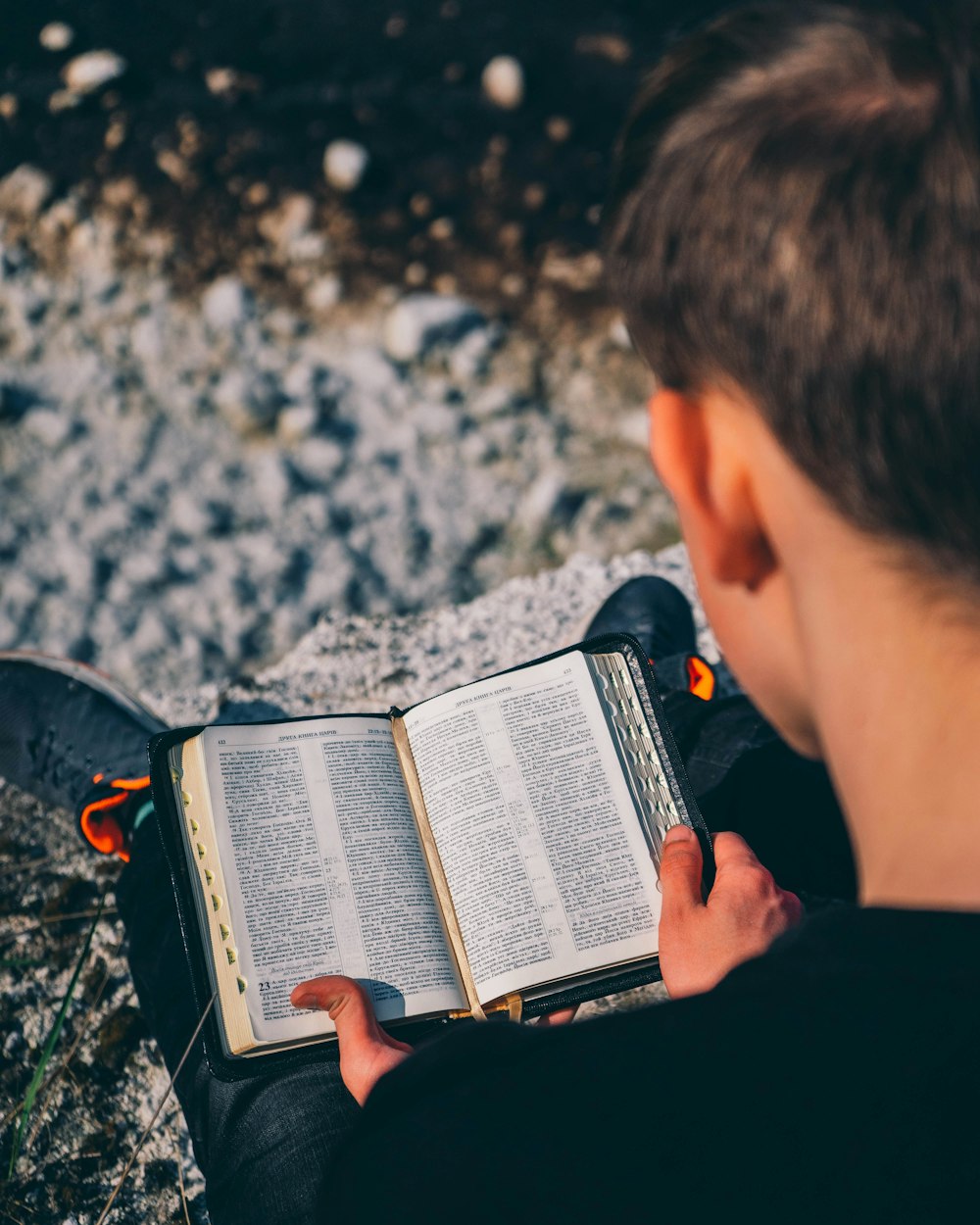 man in black jacket holding black and white book