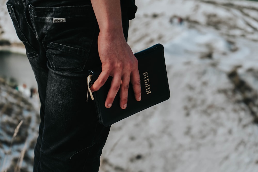 person in black denim jeans holding black smartphone