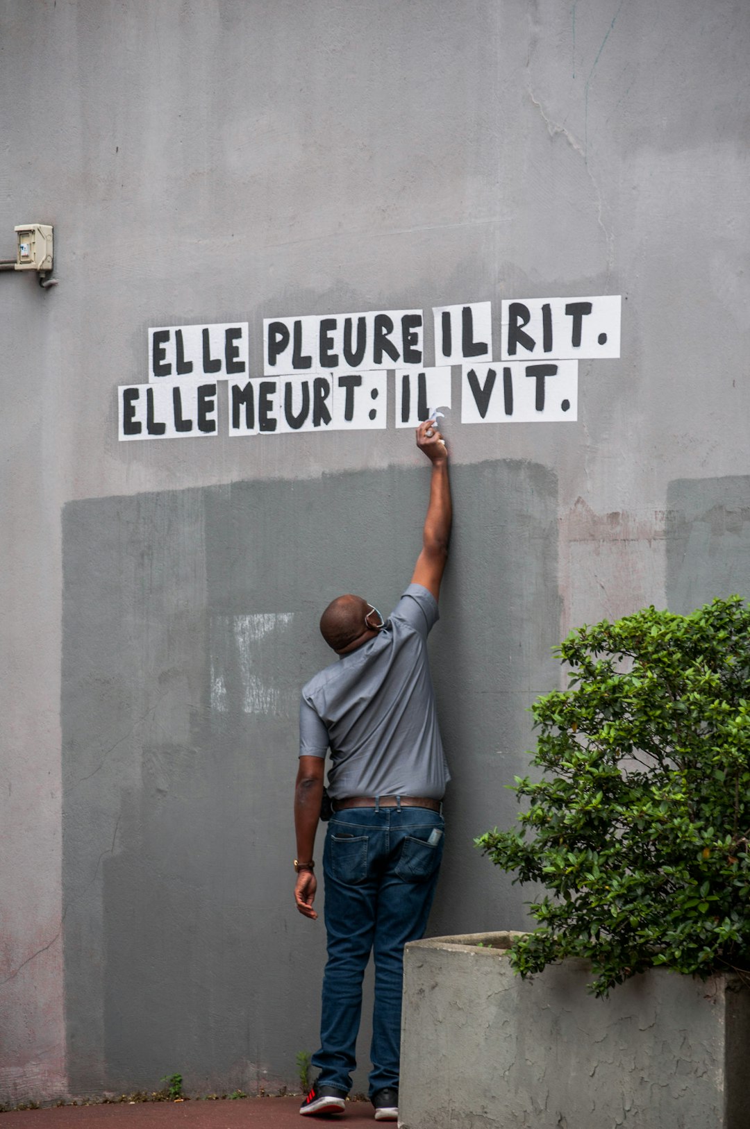 man in blue denim jeans standing in front of gray concrete wall