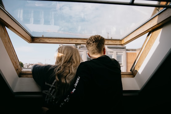 man and woman sitting on black leather couch