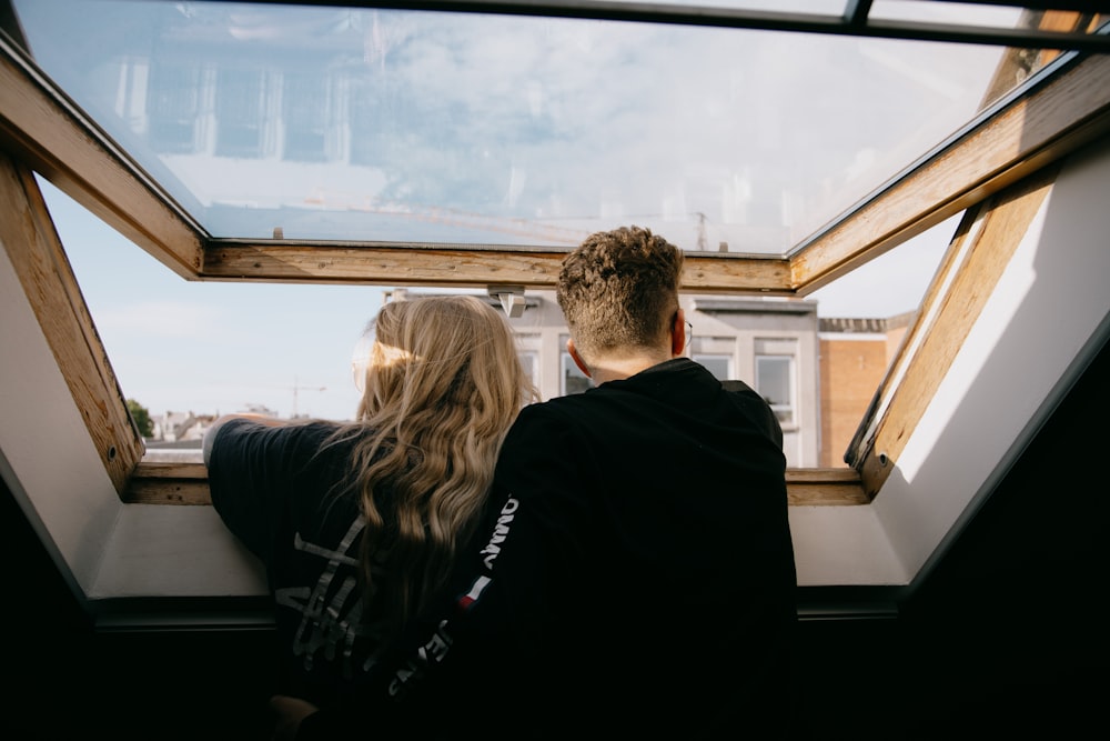 man and woman sitting on black leather couch