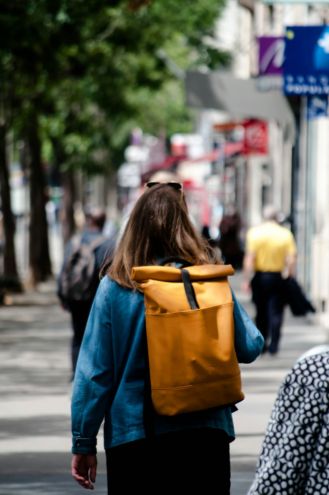 woman in blue jacket walking on sidewalk during daytime