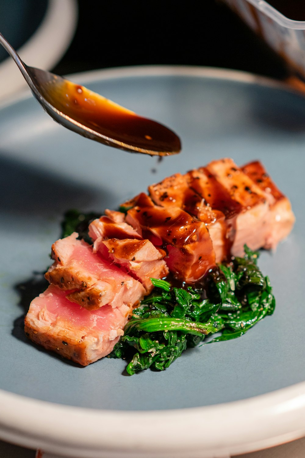 raw meat with green vegetable on black plate